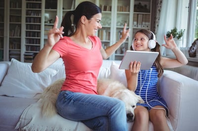 Excited mother and daughter using digital tablet and dancing at home